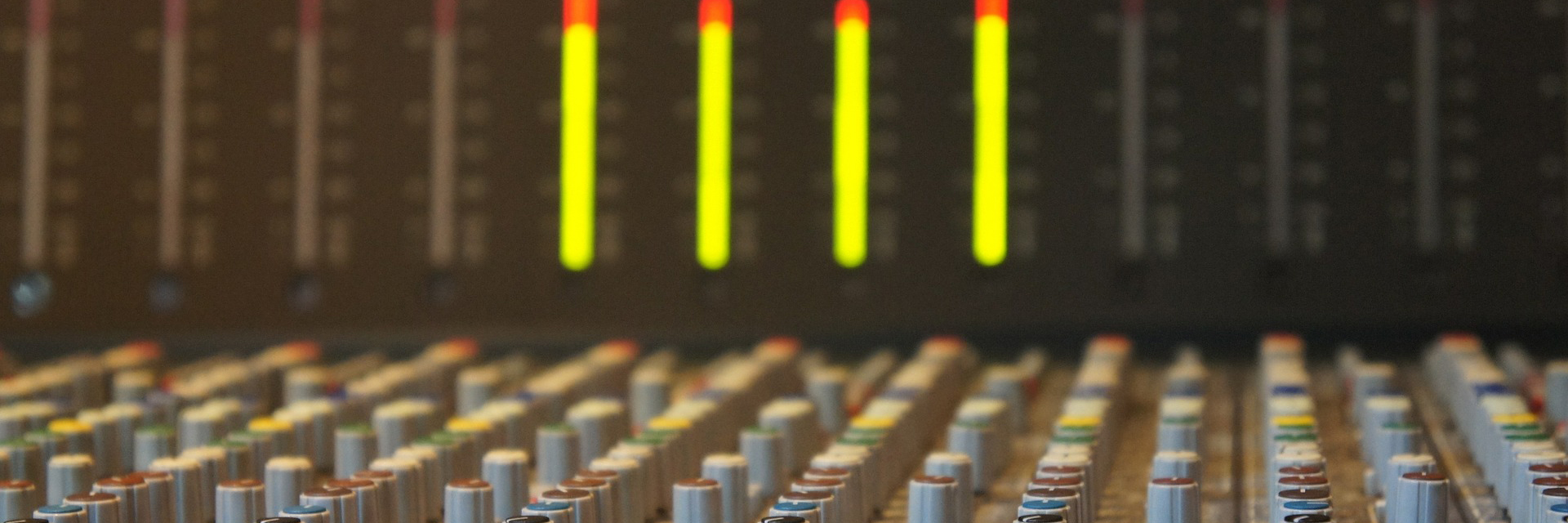 Dials on a mixing board, soft focus red and yellow lights in the background